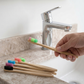 A hand taking a fresh bamboo toothbrush from the remaining brushes of the set