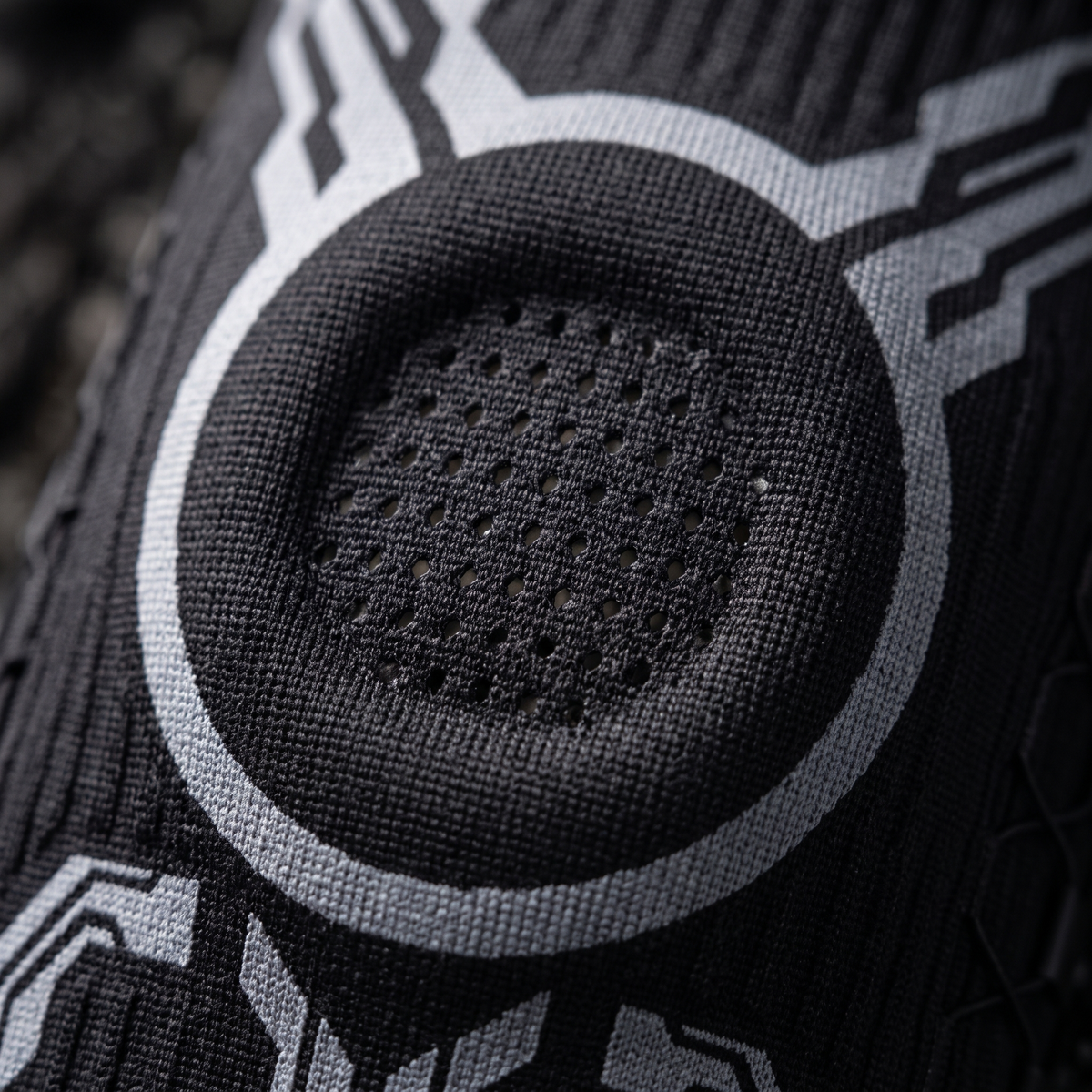 Close detail of the knit weave, grey ring graphic and dotted breathable panel of the knee sleeve