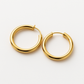 Front view of two small gold hoops on a pale stone surface
