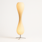 Twisted spiral wood slat lamp switched on, warm light glowing through the slats