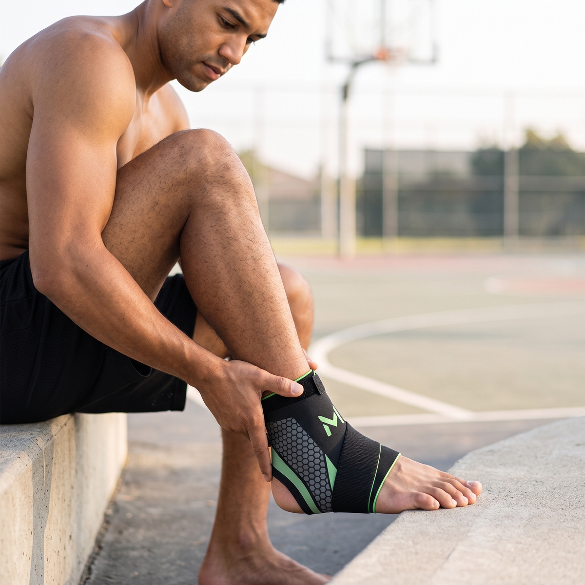 Man on an outdoor basketball court wearing the green trim thin ankle brace