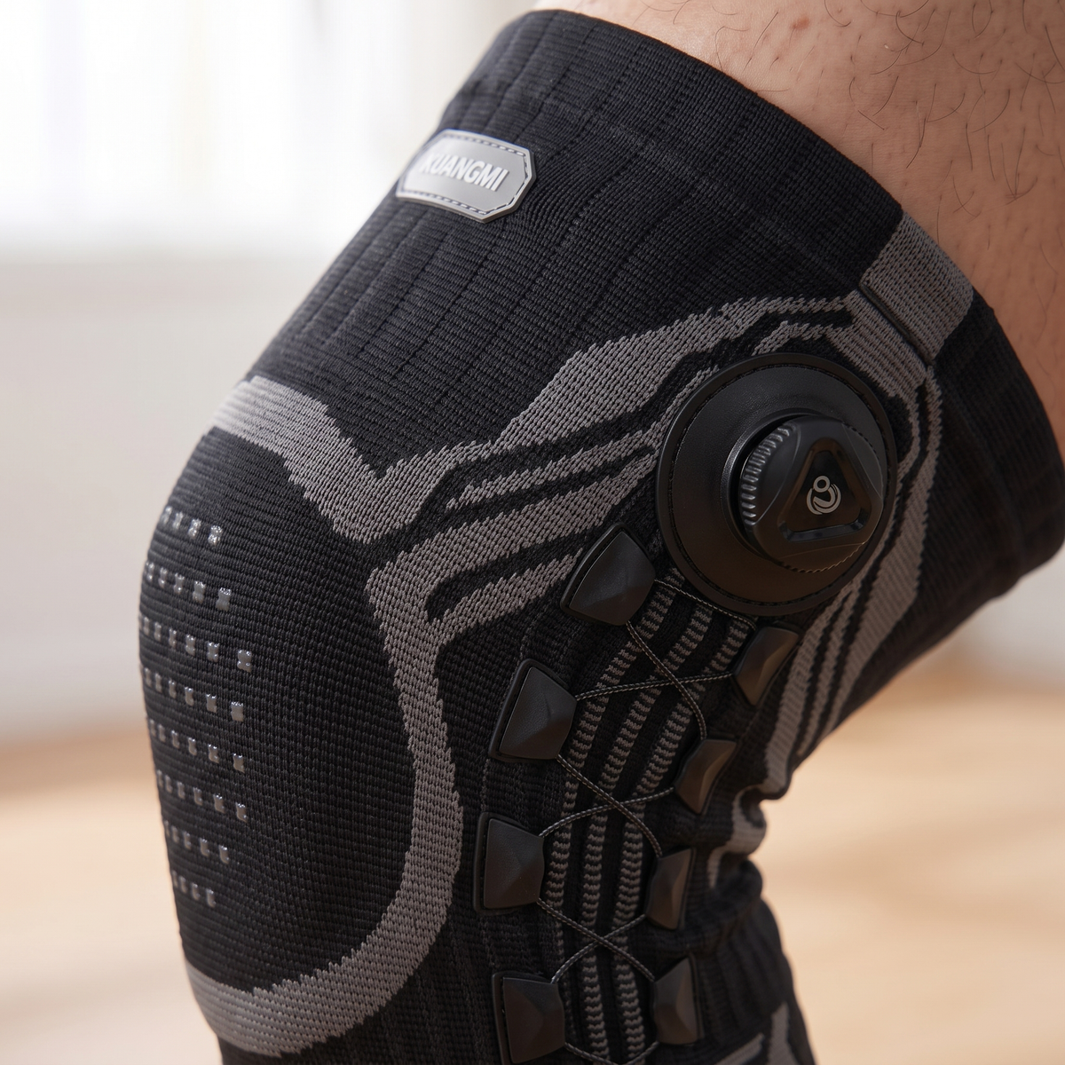 Close macro of the black rotary knob and cross lacing of the KUANGMI knee brace