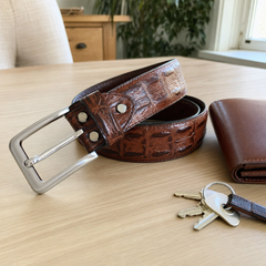 Customer photo of the reddish brown crocodile pattern leather belt on a table
